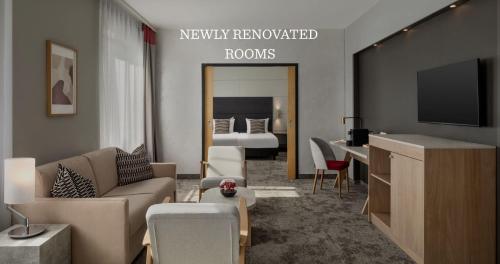 a living room with a tv and a bedroom at Ramada by Wyndham Essen in Essen