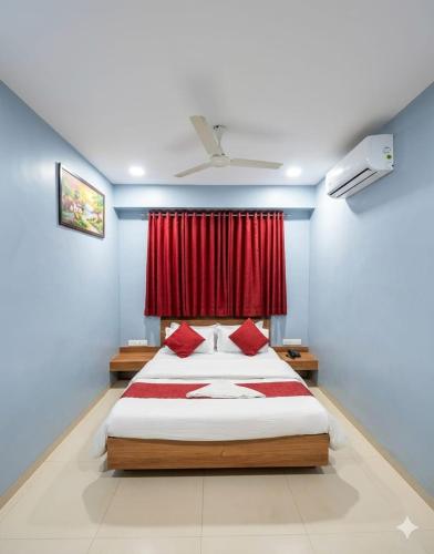a bedroom with a bed with a red curtain at Hotel Happinex Inn in Surat