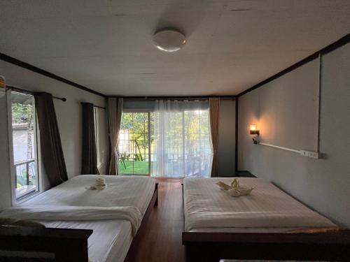 two beds in a room with a window at Khaosok River Camp in Khao Sok National Park