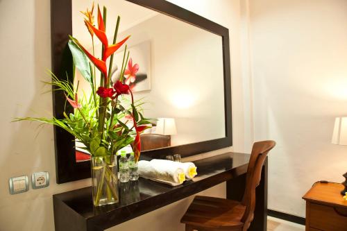 a vase with flowers on a table in a hotel room at Jepun Bali Hotel in Kuta