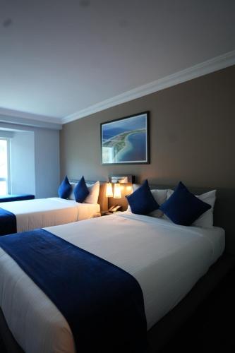 a hotel room with two beds with blue pillows at Hotel & Casino Internacional Valencia in Valencia