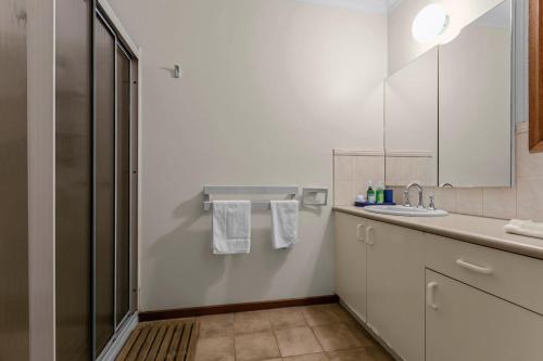 a white bathroom with a sink and a mirror at Paradise on Sheerwater in Paynesville