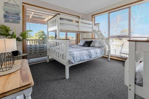 a bedroom with a white bunk bed and windows at Paradise on Sheerwater in Paynesville