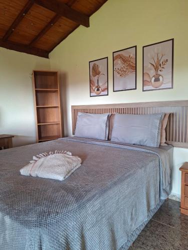 a bedroom with a large bed with three pictures on the wall at Pouso Canarinho in Carrancas