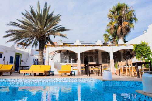 a resort with a pool and a table and chairs at Riad Dar Sarah in Taghazout