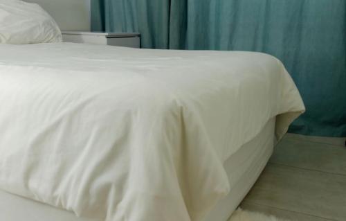 a bed with a white bedspread on top of it at Ultimate Lotus in Manzini