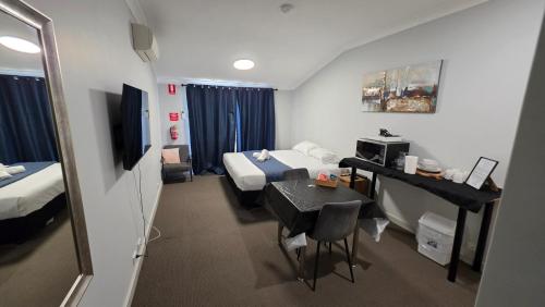 a hotel room with two beds and a table and a television at Bunbury Stay at Sanctuary Resort Strata in Bunbury