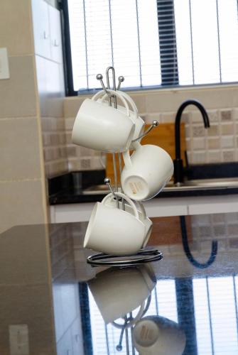 a group of white pots and pans hanging from a kitchen counter at Ultimate Lotus in Manzini