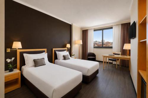a hotel room with two beds and a desk at City Life Hotel Poliziano, by R Collection Hotels in Milan