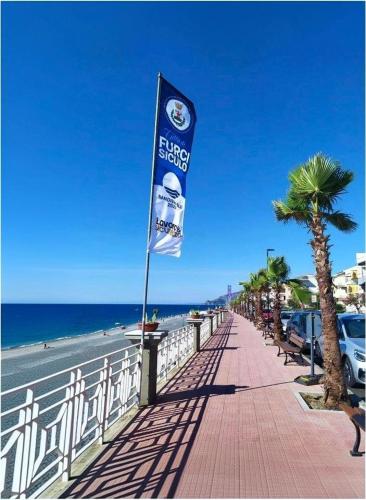 a flag on a sidewalk next to the beach at La Terrazza Bella Sicula in Furci Siculo