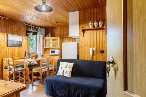 a living room with a couch and a kitchen with a table at Betù Holiday Apartment in Castello di Fiemme
