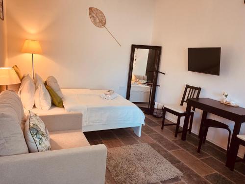 a living room with a bed and a table and a desk at Jázmin apartmanok in Pogány