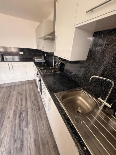 a kitchen with a stainless steel sink and white cabinets at 3 Bedroom Central Apartment in Goodmayes