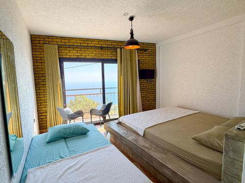 a bedroom with two beds and a large window at Alınca Elm Pansiyon in Fethiye