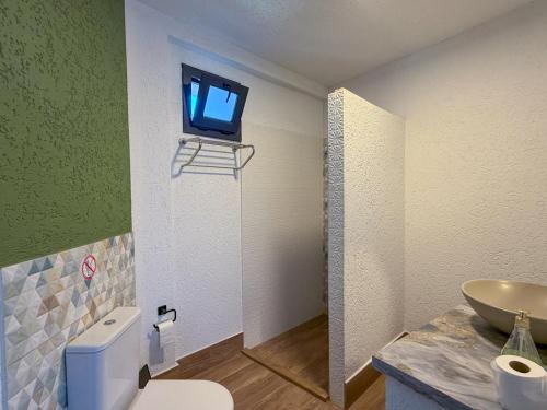 a bathroom with a toilet and a tv on the wall at Alınca Elm Pansiyon in Fethiye