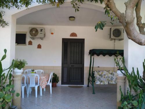 a patio with white chairs and a black door at B&B Il Melograno Salento in Torre Inserraglio