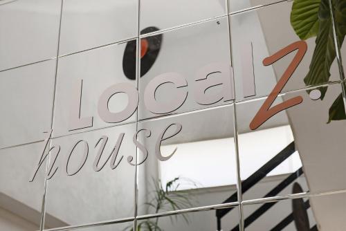 a sign for a coffee house on a tile wall at Localz House- Trumpeldor Beach in Tel Aviv