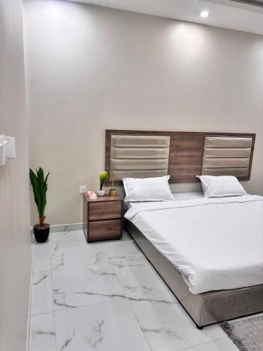 a bedroom with a large bed with a wooden headboard at ايراد للشقق - النور in Dammam