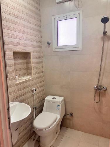 a bathroom with a toilet and a sink and a window at ايراد للشقق - النور in Dammam