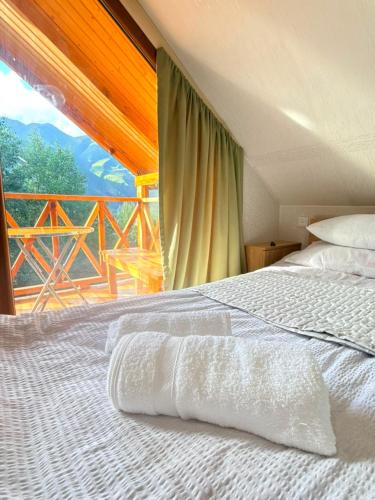 a bedroom with a white bed and a balcony at SymphonyA in Gorists'ikhe