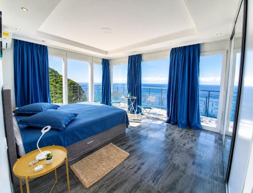 a bedroom with blue curtains and a bed with a table at Private Sea View with Infinity Pool in VILLA NERIN Zagora in Zagora