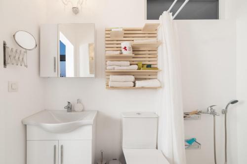 a white bathroom with a sink and a mirror at Dream View Loft in Lithakia