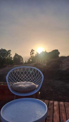 a blue chair sitting on a deck with the sunset at Refugio la Resiliencia in Algarrobo