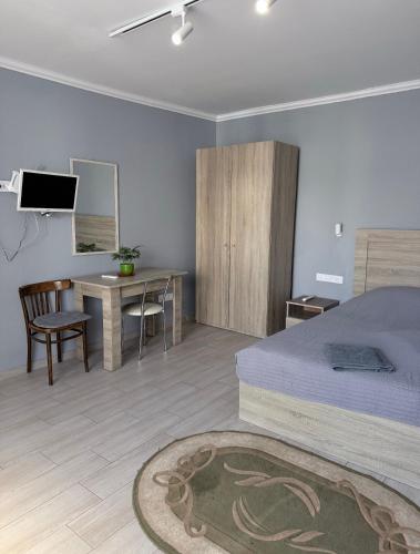 a bedroom with a bed and a table and a desk at Бухта in Nova Dofinivka