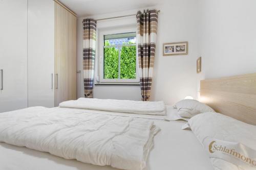 two beds in a white bedroom with a window at Haus 50 in Röbel