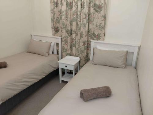 two twin beds in a room with a table at Nguni Cottage in Graaff-Reinet