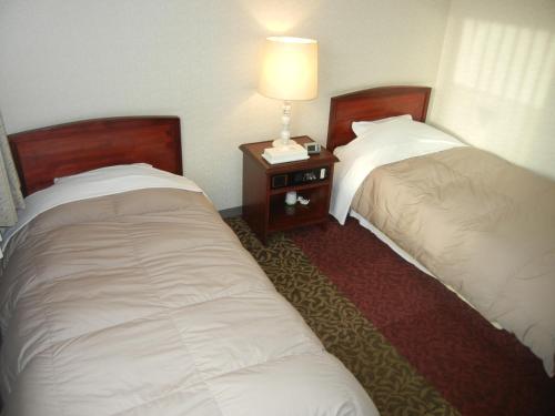 two beds in a hotel room with a lamp on a table at Hotel CROWN HILLS MIYOSHI in Miyoshi