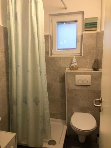 a bathroom with a toilet and a shower curtain at FEWO Kutsch Watt Nr.3 in Cuxhaven