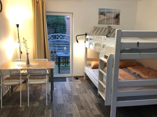 a bedroom with bunk beds and a table and a dining room at FEWO Kutsch Watt Nr.3 in Cuxhaven