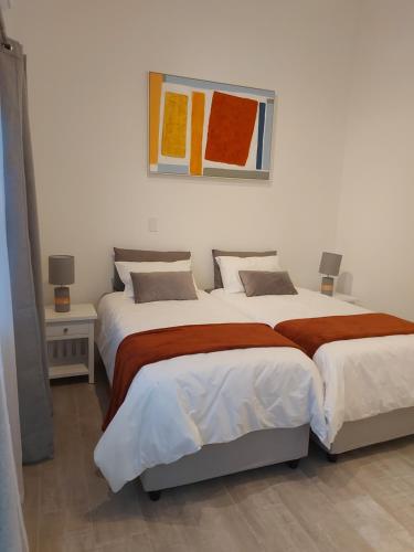 a bedroom with two beds and a painting on the wall at Sunset Dunes in Cape Town