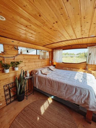 a bedroom with a large bed in a wooden cabin at Green Bus in Beit Hillel