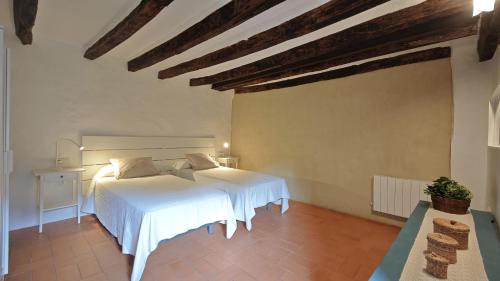 a bedroom with a white bed in a room at Ca La Remei i Can Benet in Els Hostalets d'en Bas