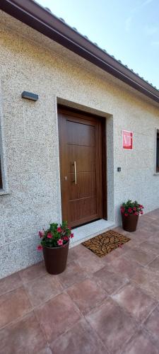 a building with a wooden door and two potted plants at Lar do Cacheiro in Meaño