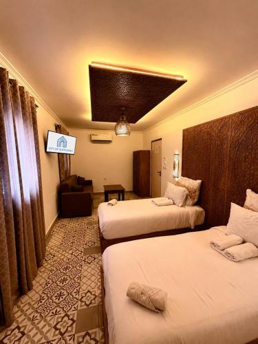 a hotel room with two beds and a television at Ahlan Riad Chefchaouen in Chefchaouen