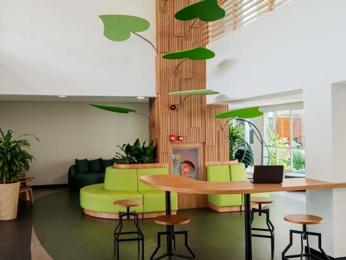 a living room with a table and green chairs at Ibis Styles Campinas Alphaville in Campinas