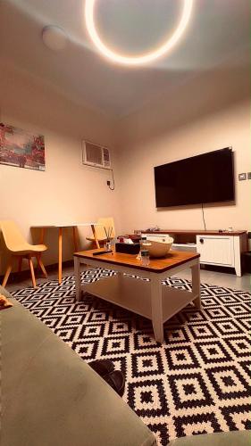 a living room with a table and a flat screen tv at أوريانا Oriana in Jeddah