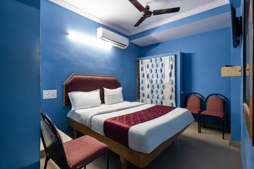 a bedroom with blue walls and a bed and chairs at Hotel Swarna Mayuri in Guntūr
