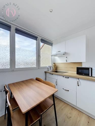 a kitchen with a wooden table and some windows at Le Studio Bleu - Dernier etage & Confort in Coudekerque-Branche