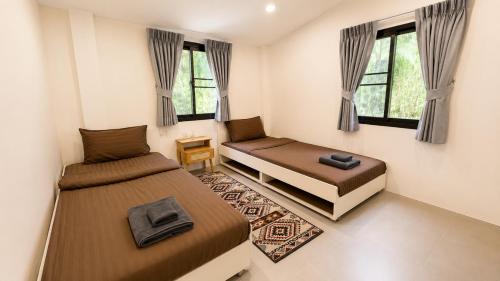 two beds in a small room with windows at Sawan villa in Hinkong