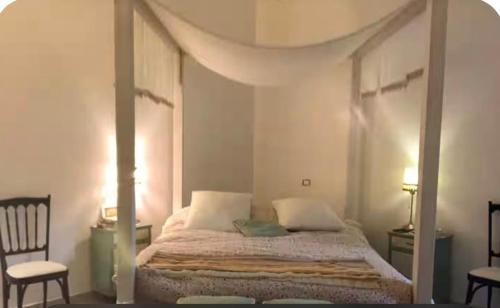 a bedroom with a canopy bed and a chair at Latte e Menta House in Casale