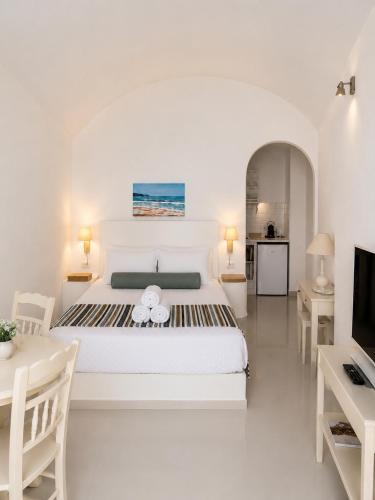 a white bedroom with a large bed and a television at Santorini Theasis Suites in Imerovigli