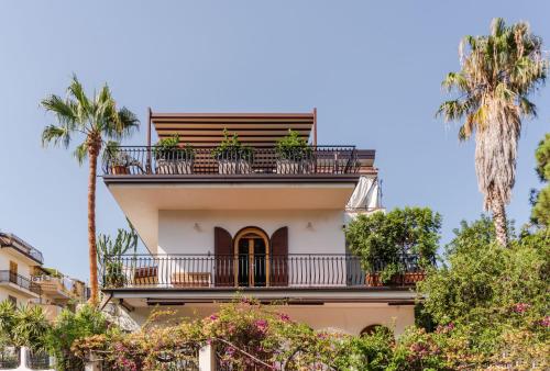 a building with a balcony and palm trees at Villa Domina by Letstay in Giardini Naxos