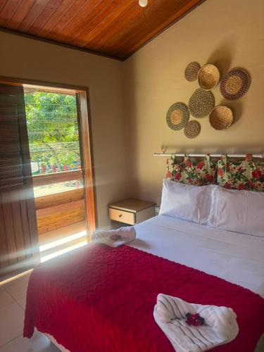 a bedroom with a bed with a red blanket and a window at Pousada Almar in Itacaré
