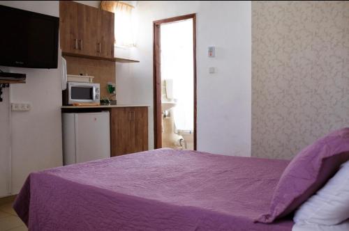 a bedroom with a purple bed and a microwave at City Center Apartments in Haifa
