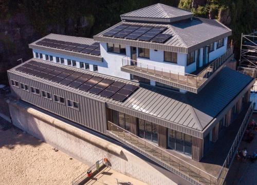 a building with solar panels on it on the beach at Harbour Stays - The Marine Centre, Saundersfoot Harbour, SA69 9HE in Saundersfoot