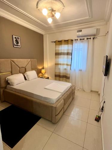 a bedroom with a bed and a window and a television at Western Suites in Douala